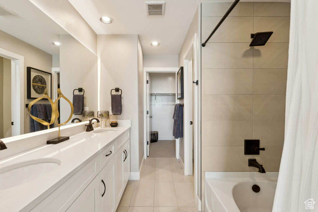 Bathroom featuring double vanity, tile patterned flooring, a spacious closet, shower / bath combo, and baseboards