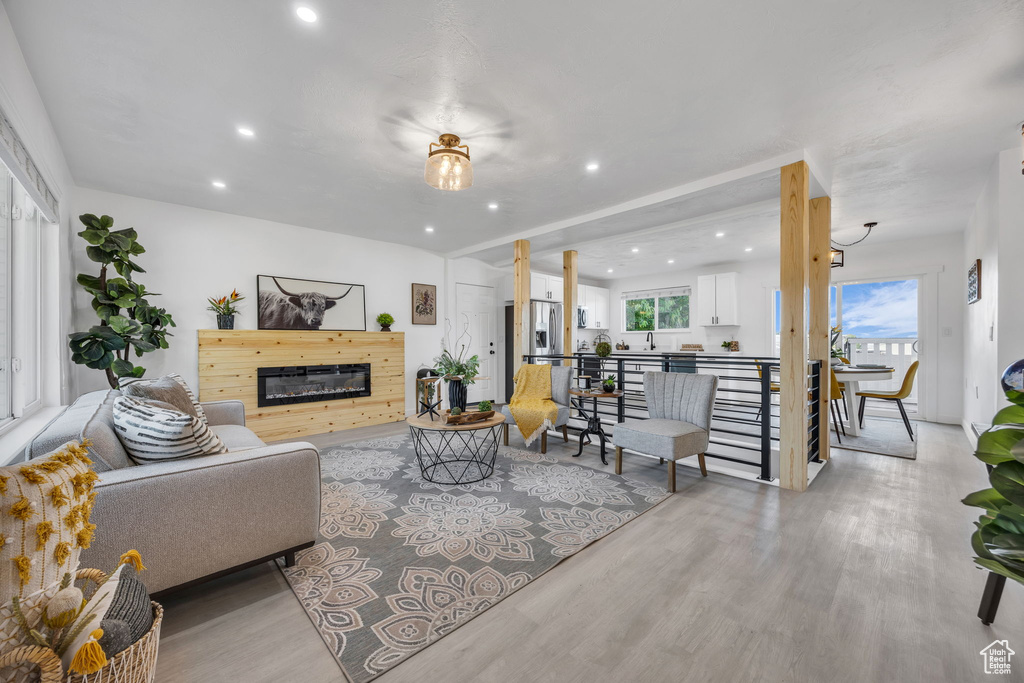 Living room featuring recessed lighting, light wood-style floors, and a glass covered fireplace