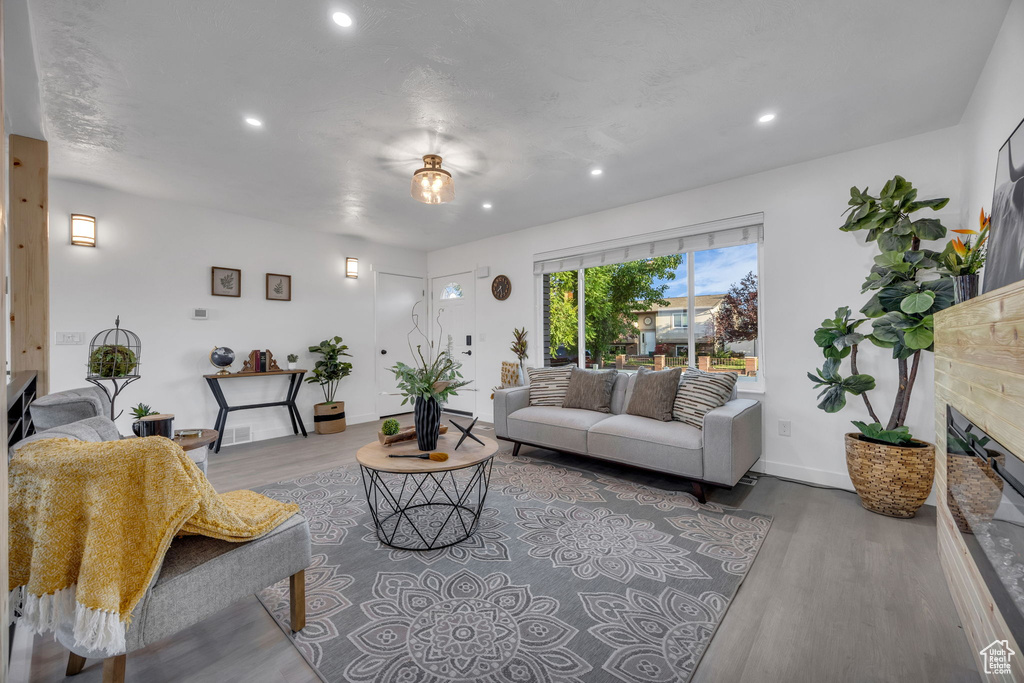 Living room featuring a glass covered fireplace, wood finished floors, recessed lighting, and baseboards