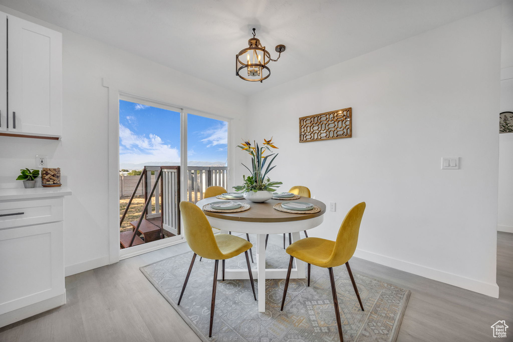 Dining room featuring light wood-style flooring, a chandelier, and baseboards