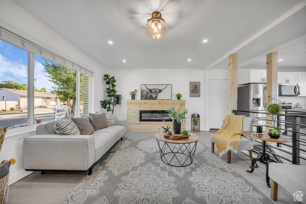 Living area featuring recessed lighting, a glass covered fireplace, baseboards, and wood finished floors