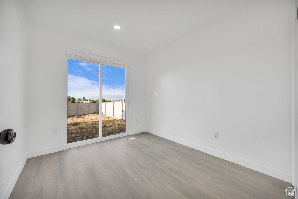 Unfurnished room with wood finished floors, baseboards, and recessed lighting