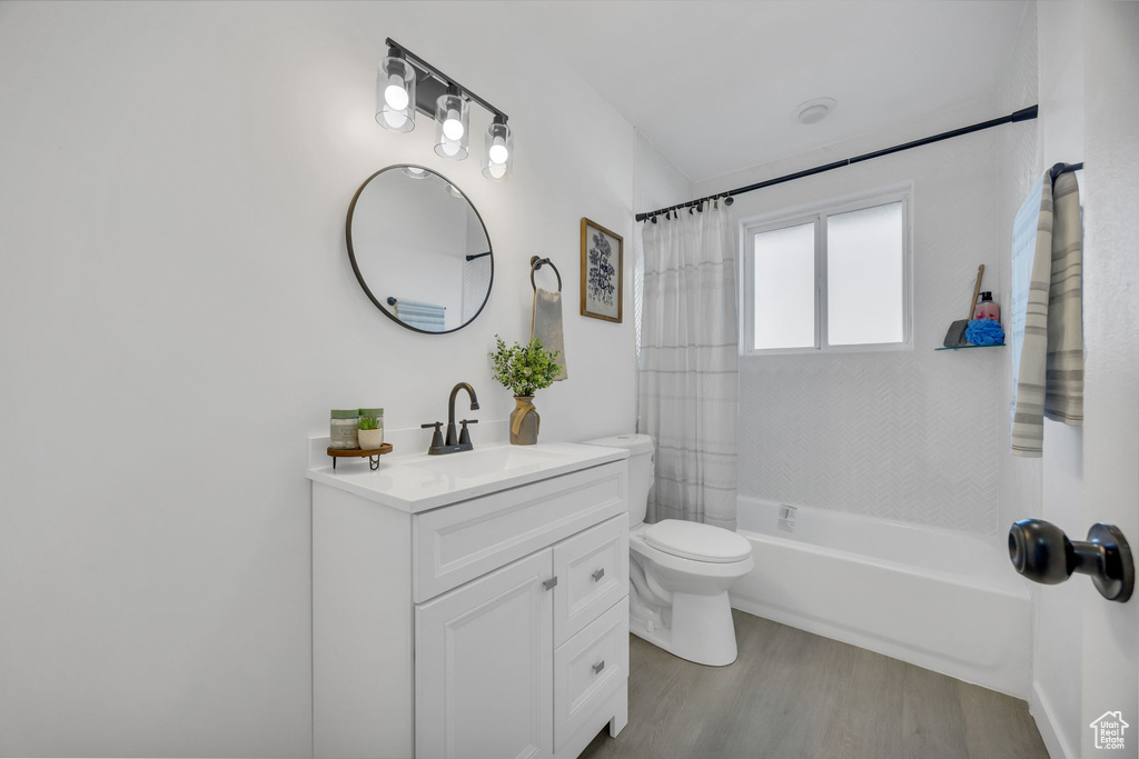 Bathroom with vanity, wood finished floors, toilet, and shower / bath combo