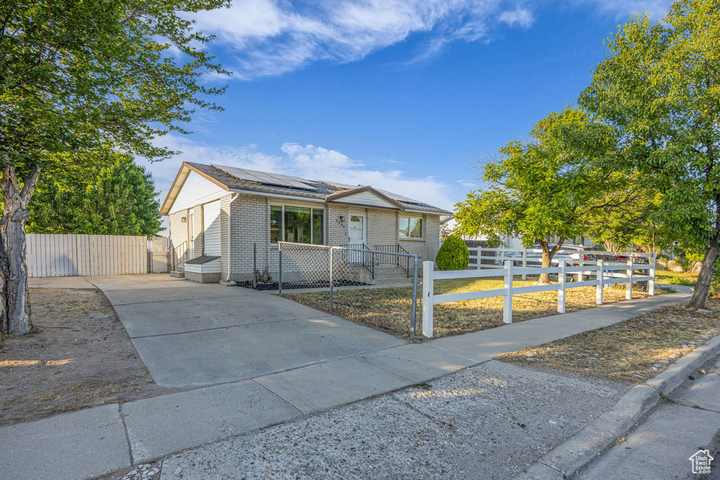 View of front of home featuring solar panels, a fenced front yard, brick siding, and a gate