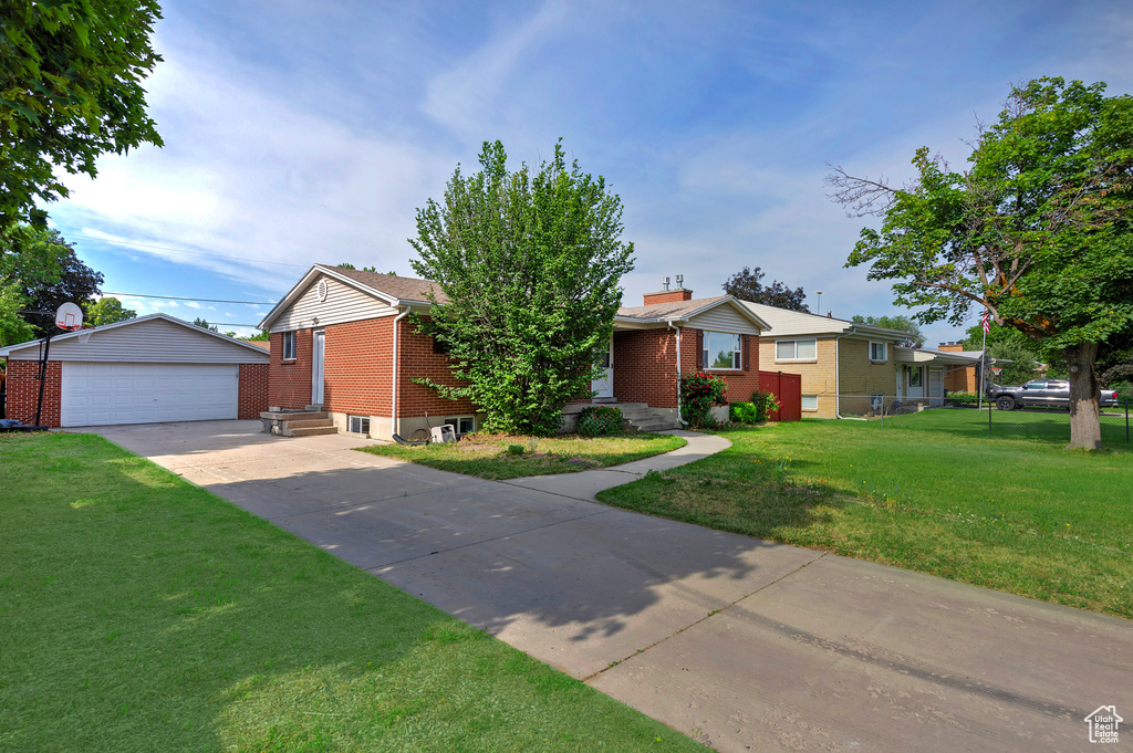 Ranch-style house featuring brick siding, an outbuilding, a detached garage, and a front yard