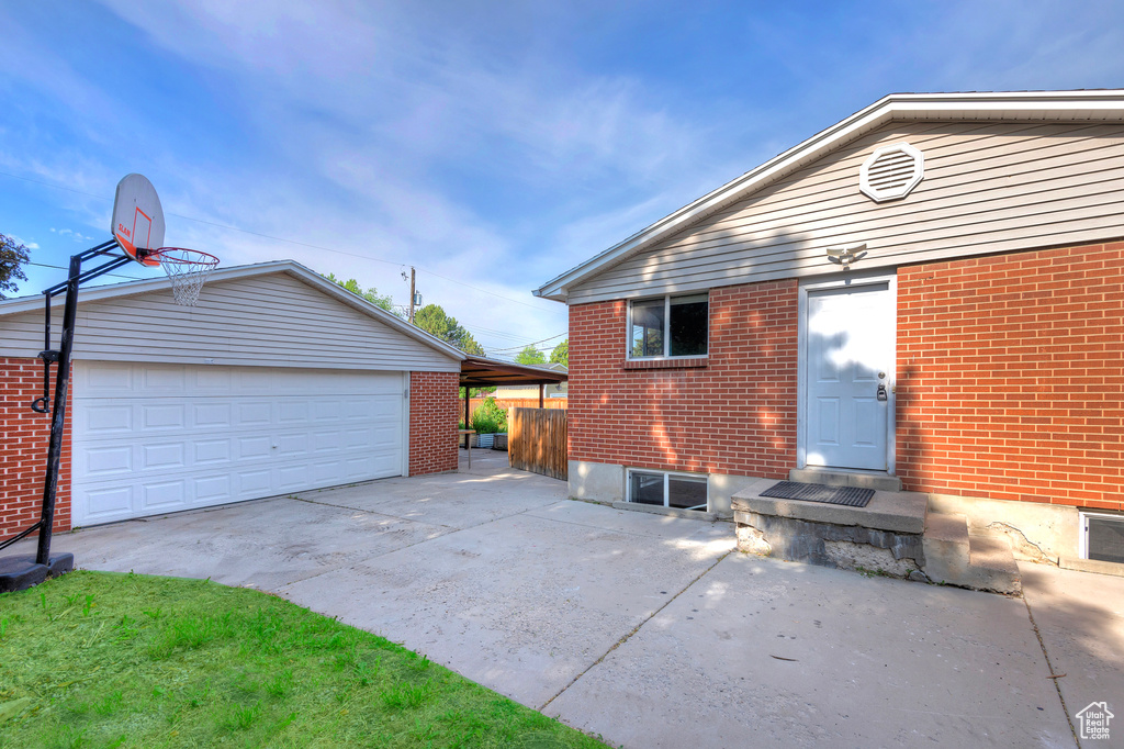 Back of property featuring an outdoor structure, brick siding, and concrete driveway