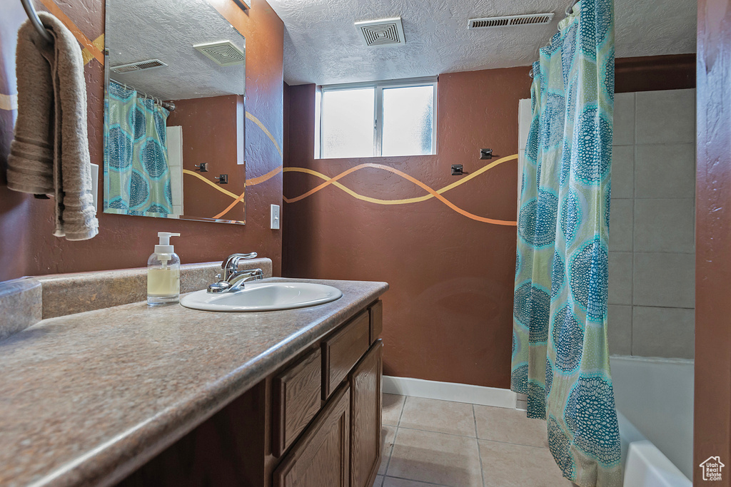 Full bathroom with vanity, tile patterned floors, shower / bath combination with curtain, and a textured ceiling