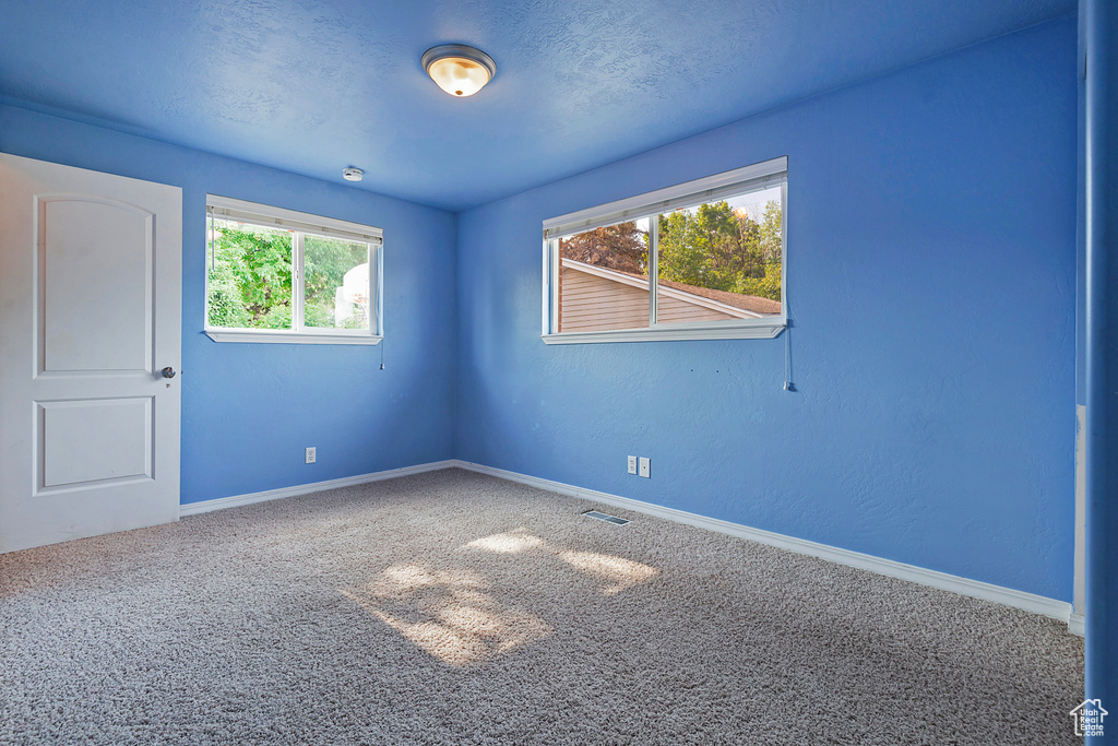 Carpeted spare room featuring baseboards