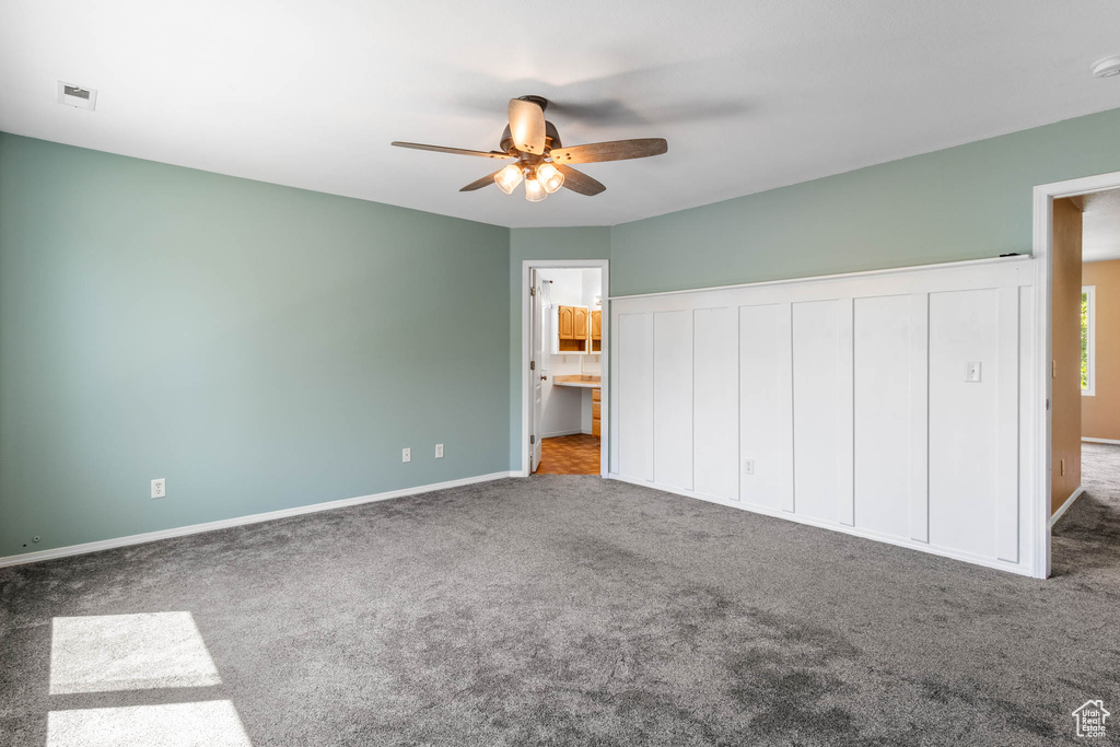 Unfurnished bedroom with carpet, baseboards, a ceiling fan, and connected bathroom