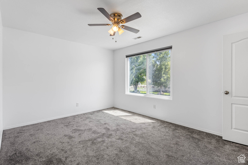 Carpeted empty room featuring ceiling fan and baseboards
