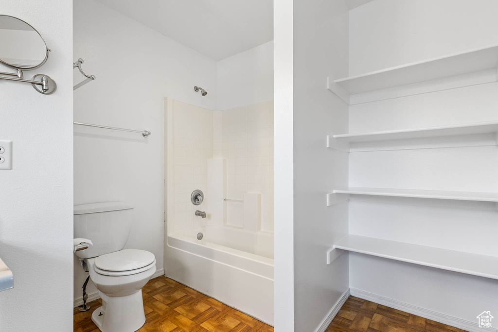 Bathroom featuring toilet, shower / bath combination, and baseboards