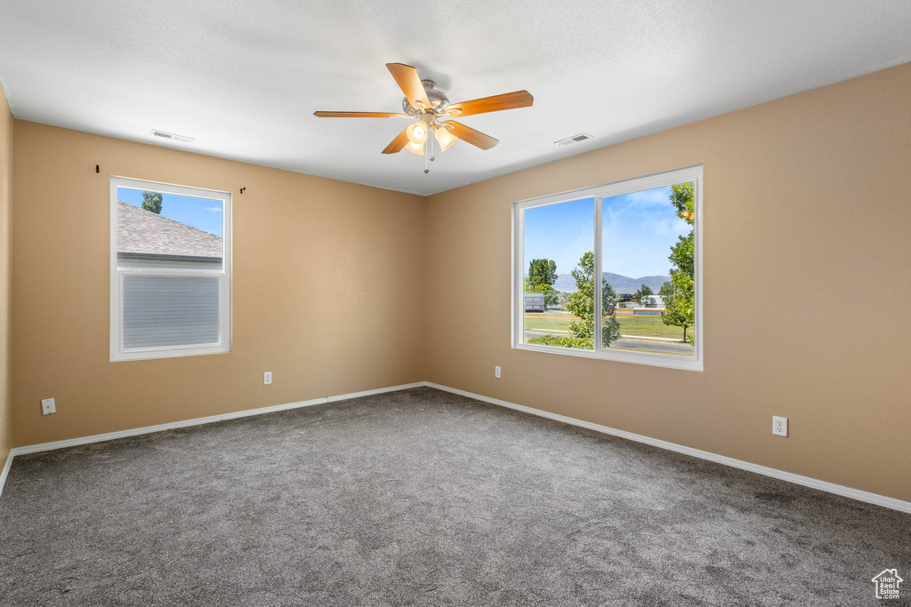 Carpeted spare room with a ceiling fan and baseboards