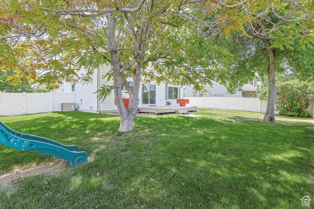 View of yard with central AC unit, a deck, and a playground