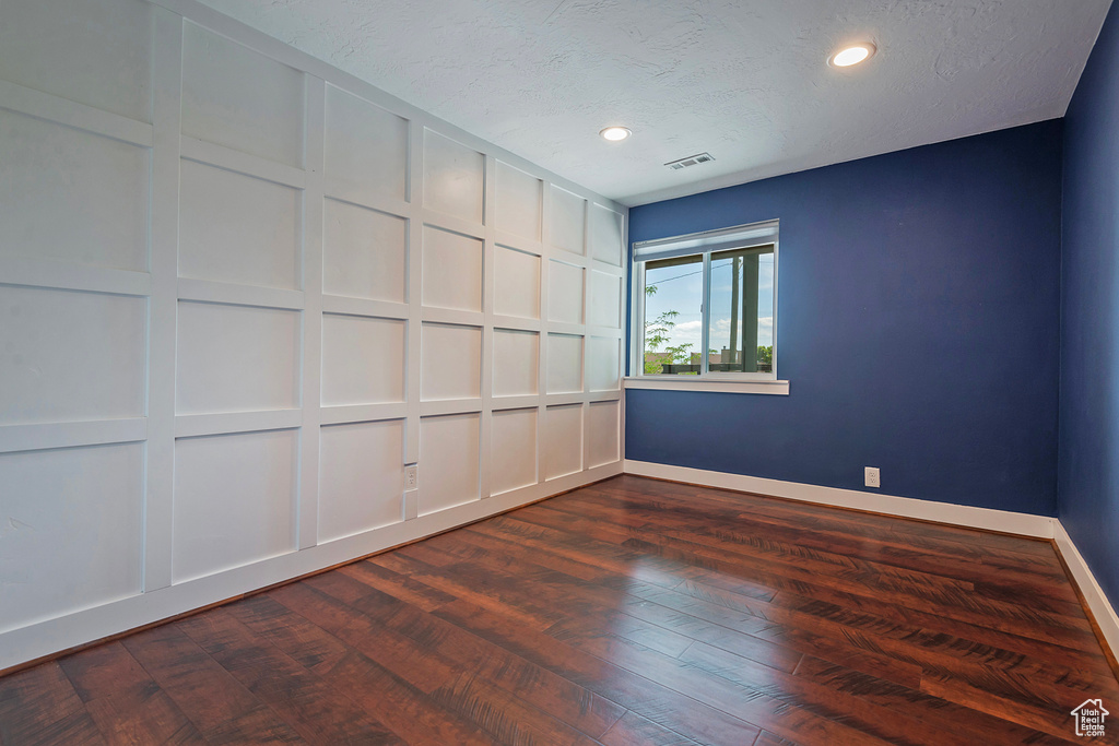 Empty room featuring baseboards, recessed lighting, dark wood-style floors, and a textured ceiling
