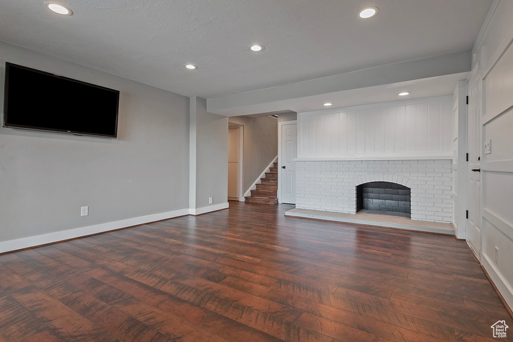 Unfurnished living room with baseboards, a fireplace, recessed lighting, wood finished floors, and stairs