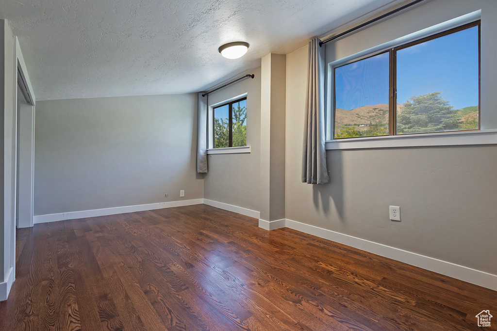 Unfurnished room featuring a textured ceiling, wood finished floors, and baseboards