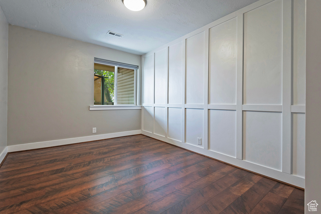 Spare room featuring dark wood-type flooring and baseboards