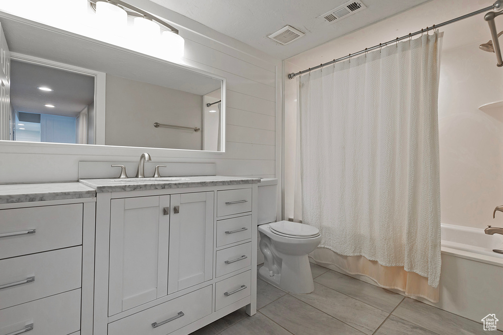 Full bath with toilet, vanity, shower / bath combo with shower curtain, and tile patterned floors