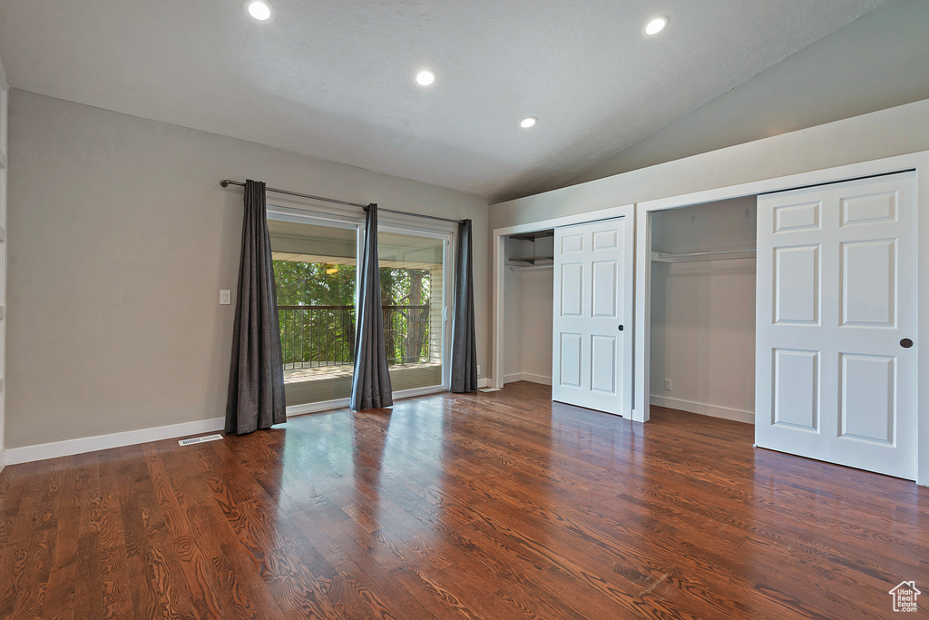 Unfurnished bedroom with two closets, lofted ceiling, recessed lighting, dark wood-type flooring, and baseboards