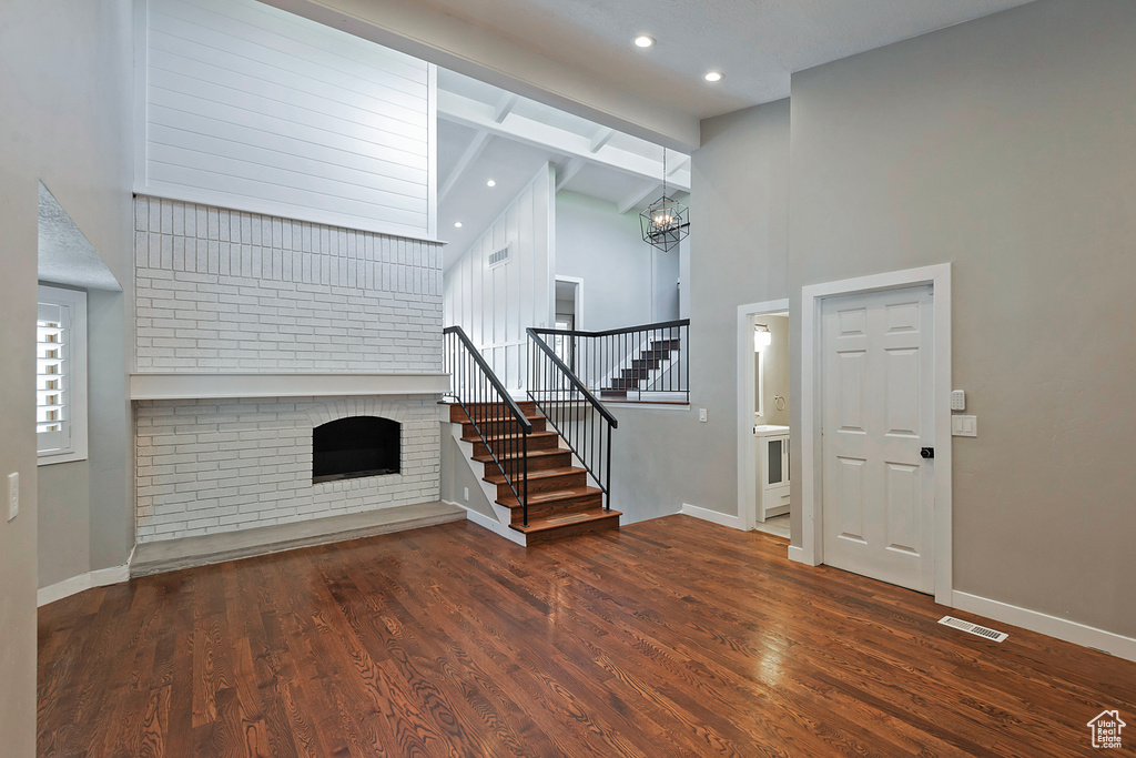 Foyer with stairway, a brick fireplace, a chandelier, a high ceiling, and baseboards