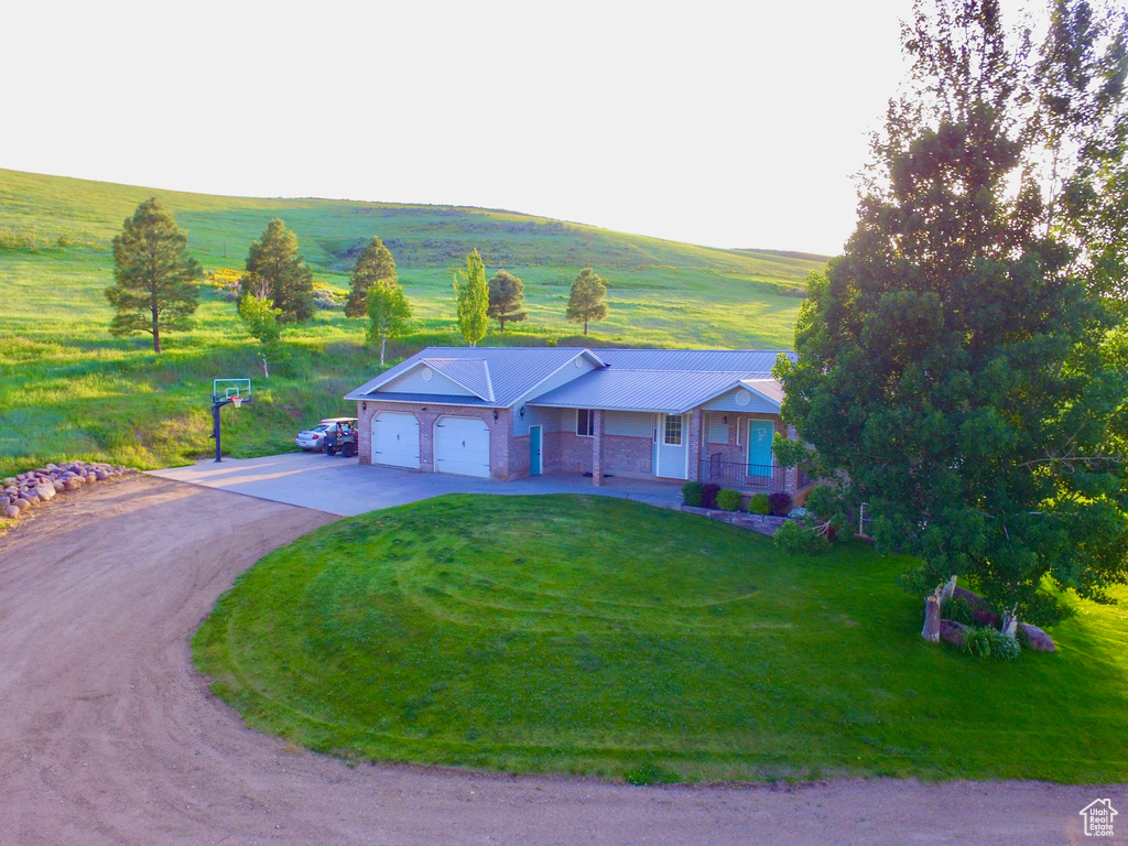 View of front of home with a garage, driveway, a front lawn, metal roof, and covered porch