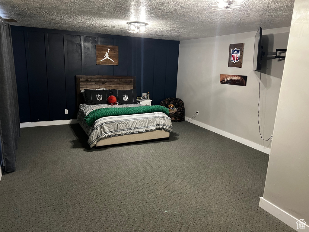Bedroom with carpet floors, baseboards, and a textured ceiling