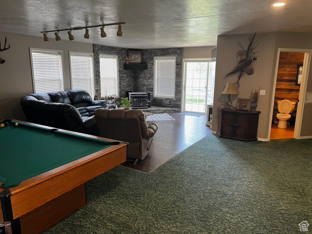 Playroom with a wood stove, a textured ceiling, billiards, carpet flooring, and wood finished floors