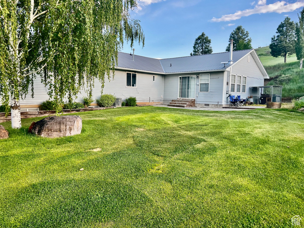 Rear view of property with a yard, metal roof, and crawl space