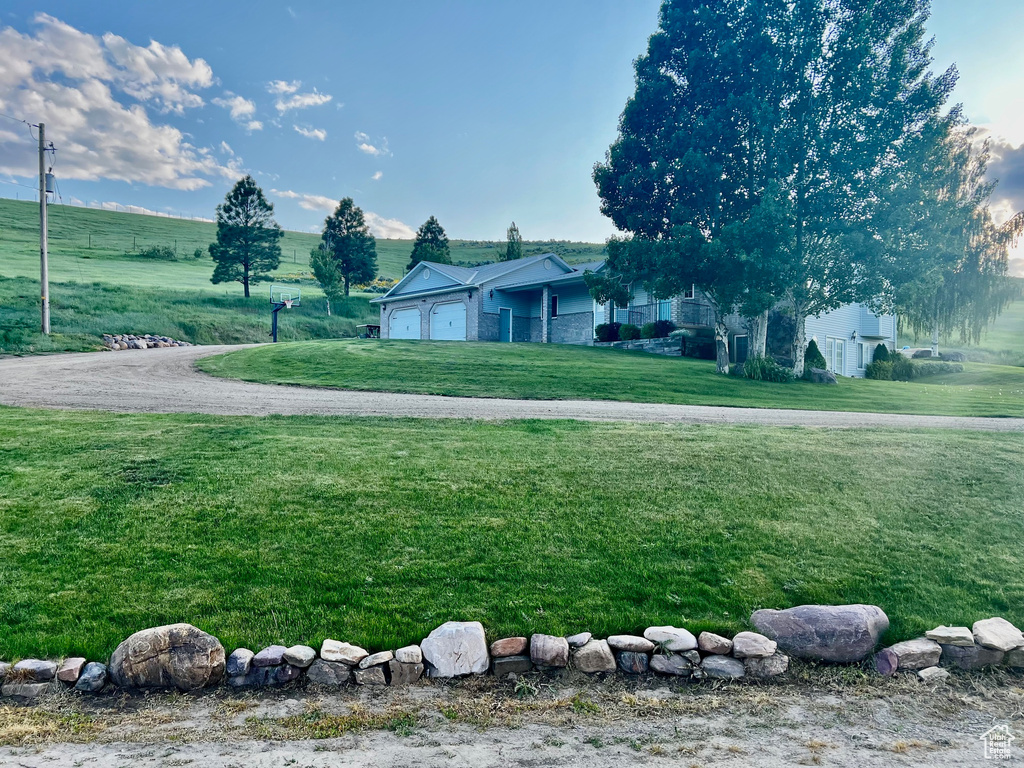 View of green lawn featuring a garage and driveway