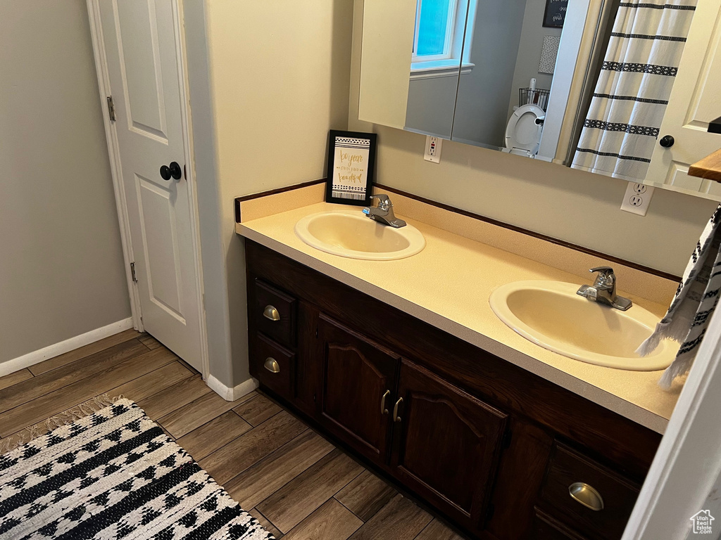 Full bath with wood finished floors, double vanity, and baseboards