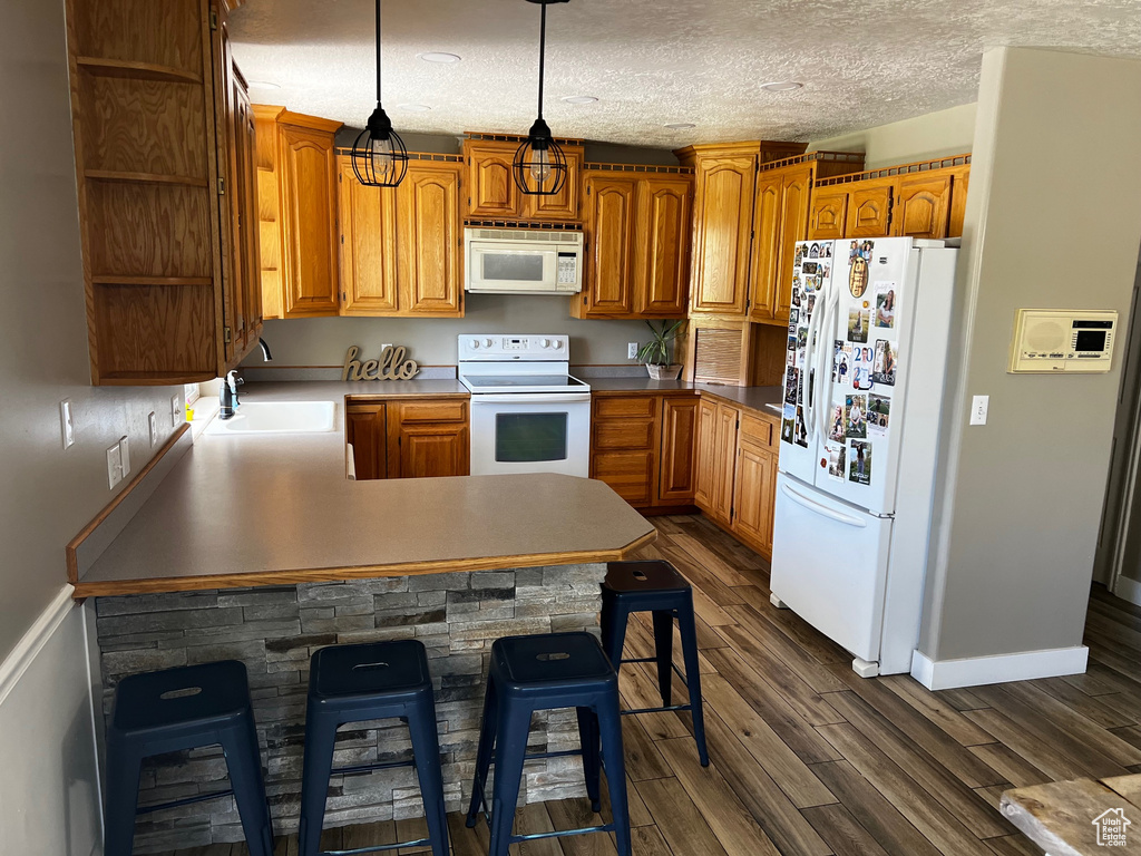 Kitchen featuring white appliances, open shelves, a sink, a peninsula, and dark wood-style flooring