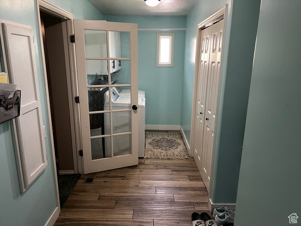 Entryway with wood finished floors, independent washer and dryer, and a textured ceiling