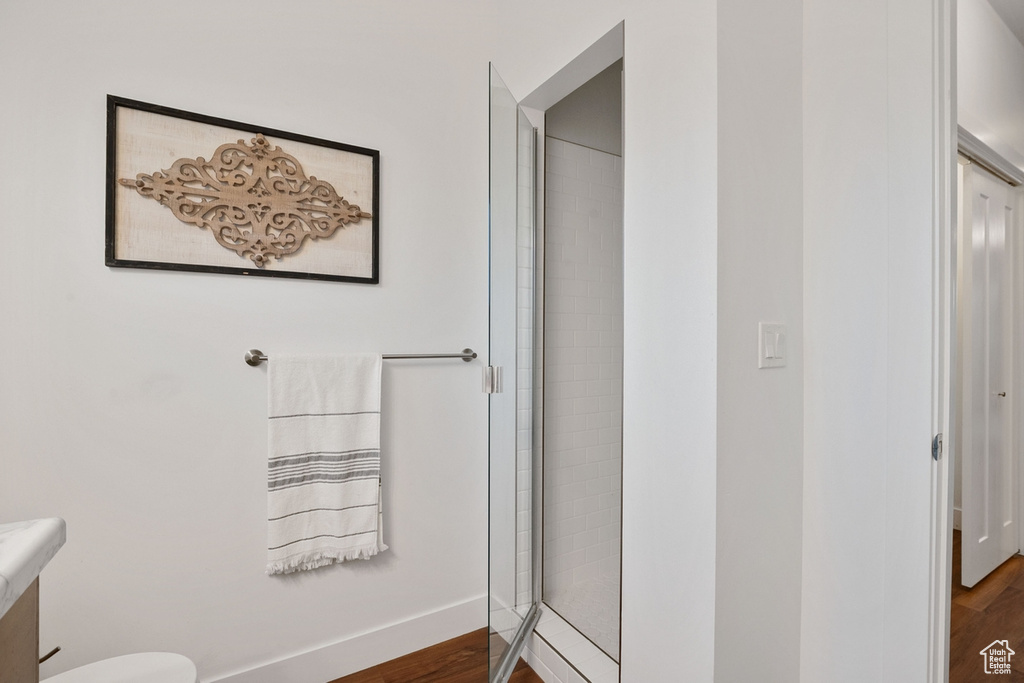 Bathroom with wood finished floors, a stall shower, vanity, and toilet