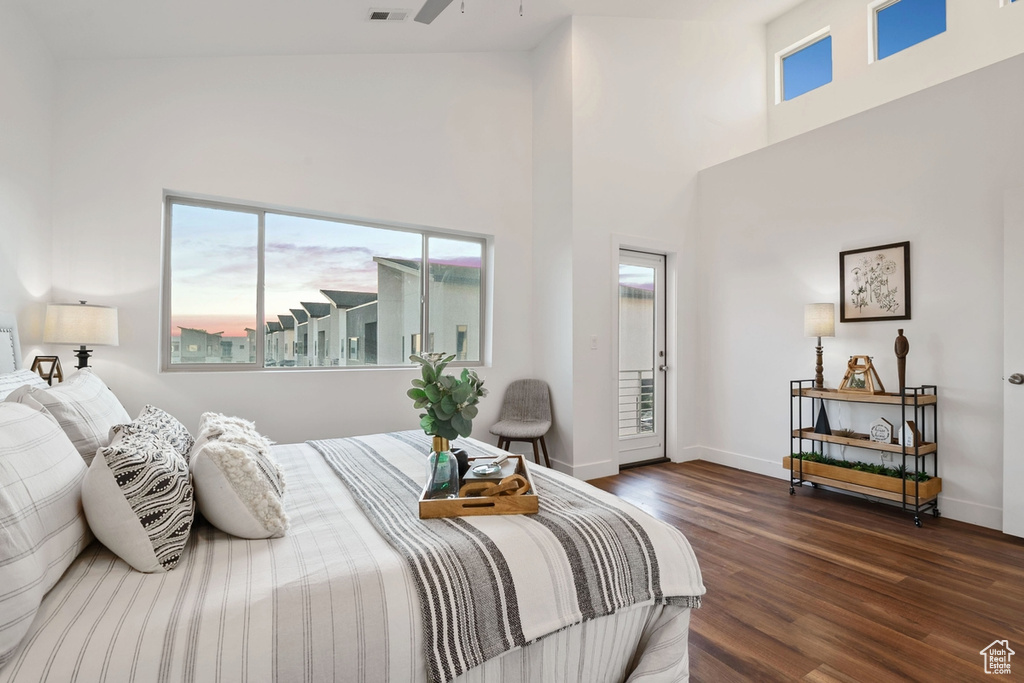 Bedroom with dark wood-style flooring, multiple windows, a high ceiling, and baseboards