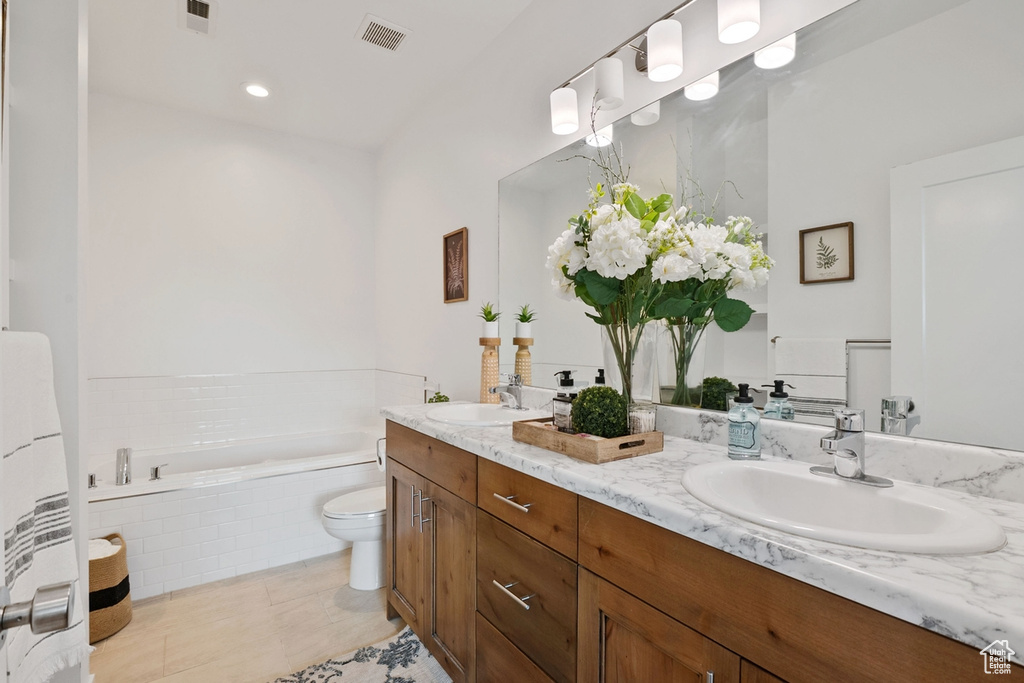 Bathroom featuring a garden tub, double vanity, toilet, and tile patterned floors