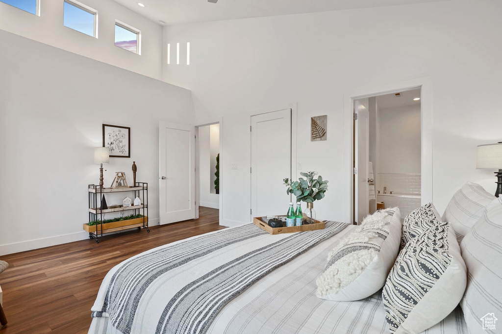 Bedroom featuring wood finished floors, baseboards, a towering ceiling, ensuite bath, and recessed lighting