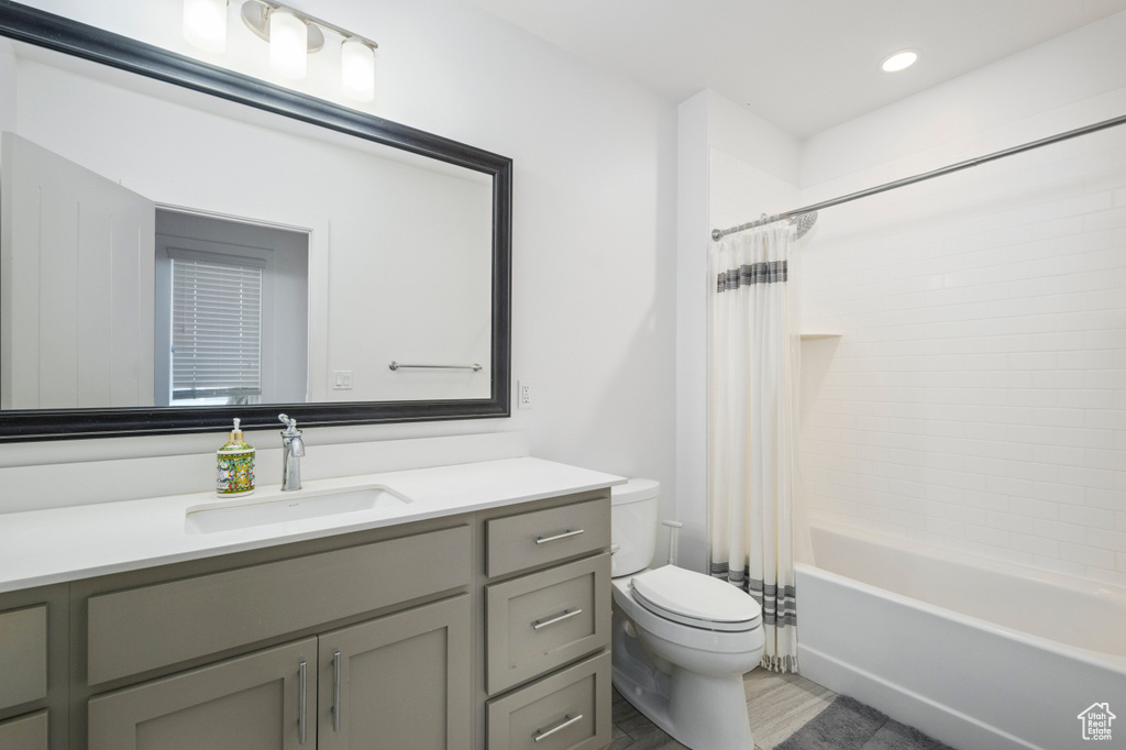 Bathroom with toilet, vanity, shower / bath combination with curtain, and wood finished floors