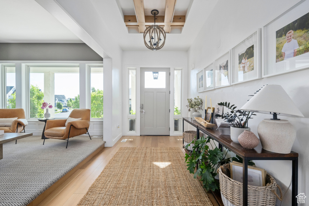 Foyer entrance with light wood-style floors, a chandelier, coffered ceiling, and beamed ceiling