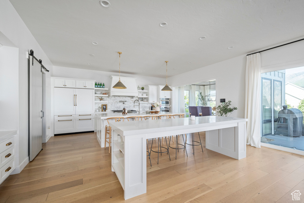 Kitchen featuring open shelves, a barn door, light wood finished floors, light countertops, and recessed lighting