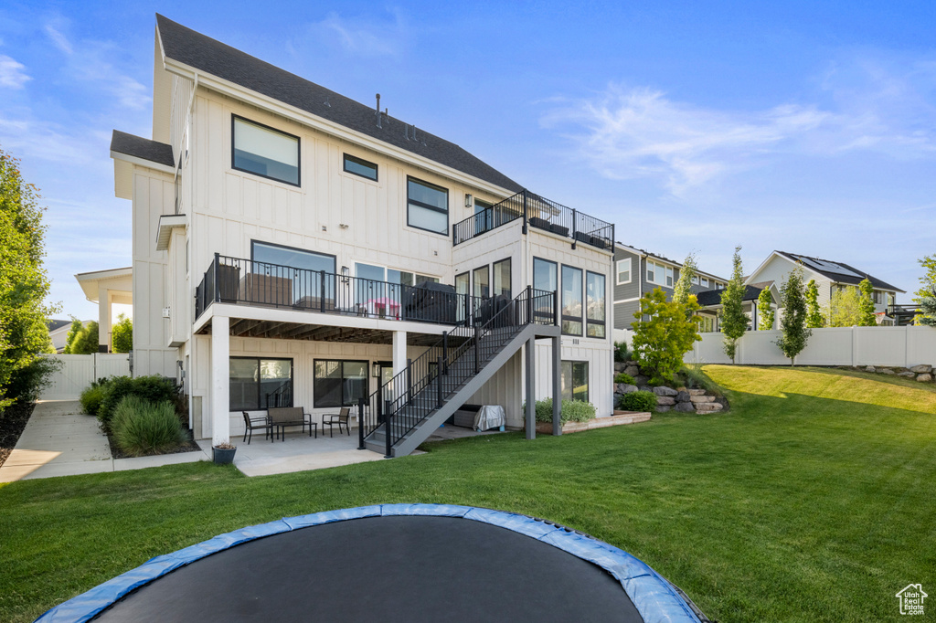 Rear view of property featuring board and batten siding, stairs, a patio area, and a balcony