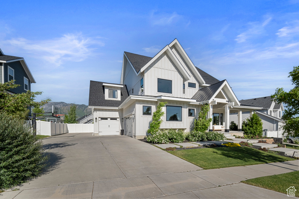 Modern inspired farmhouse with board and batten siding, driveway, an attached garage, a shingled roof, and metal roof
