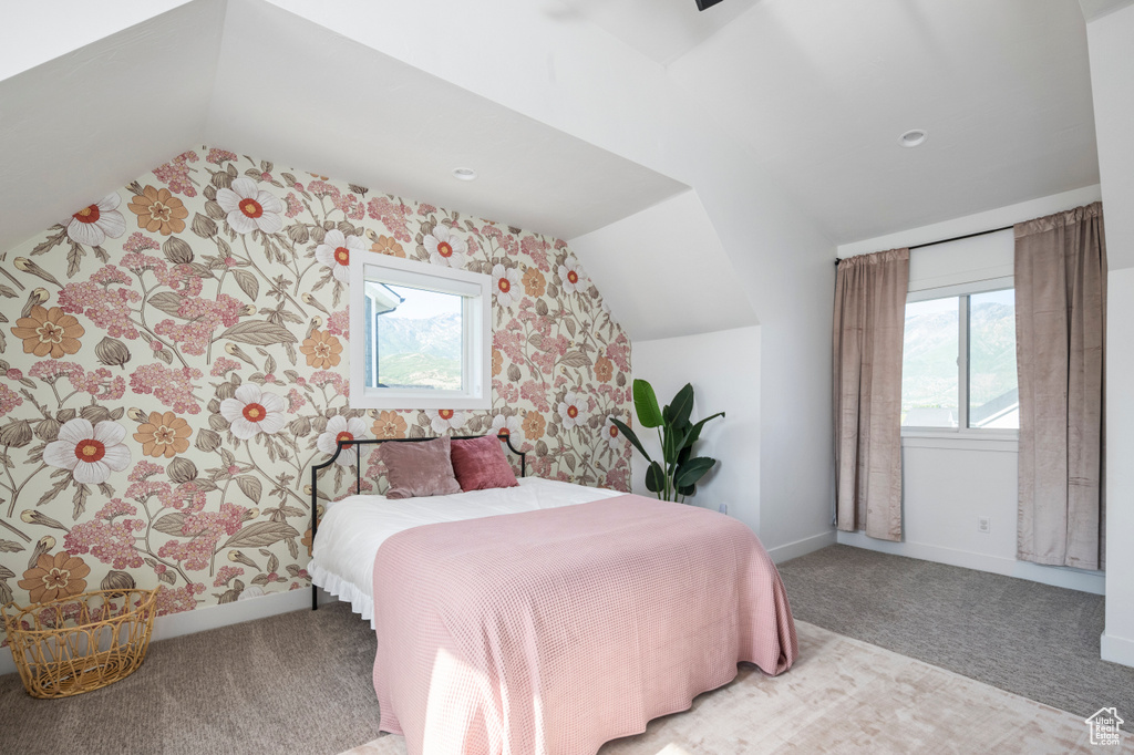Carpeted bedroom featuring vaulted ceiling, multiple windows, baseboards, and wallpapered walls