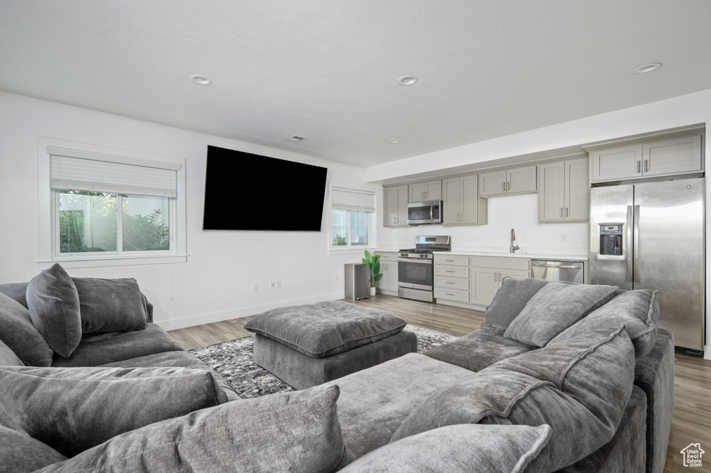 Living room with light wood-type flooring, baseboards, and recessed lighting