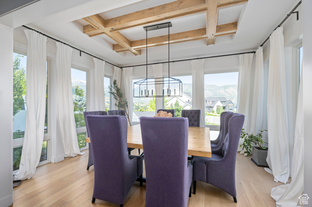 Dining room with coffered ceiling, light wood finished floors, a chandelier, beam ceiling, and a mountain view