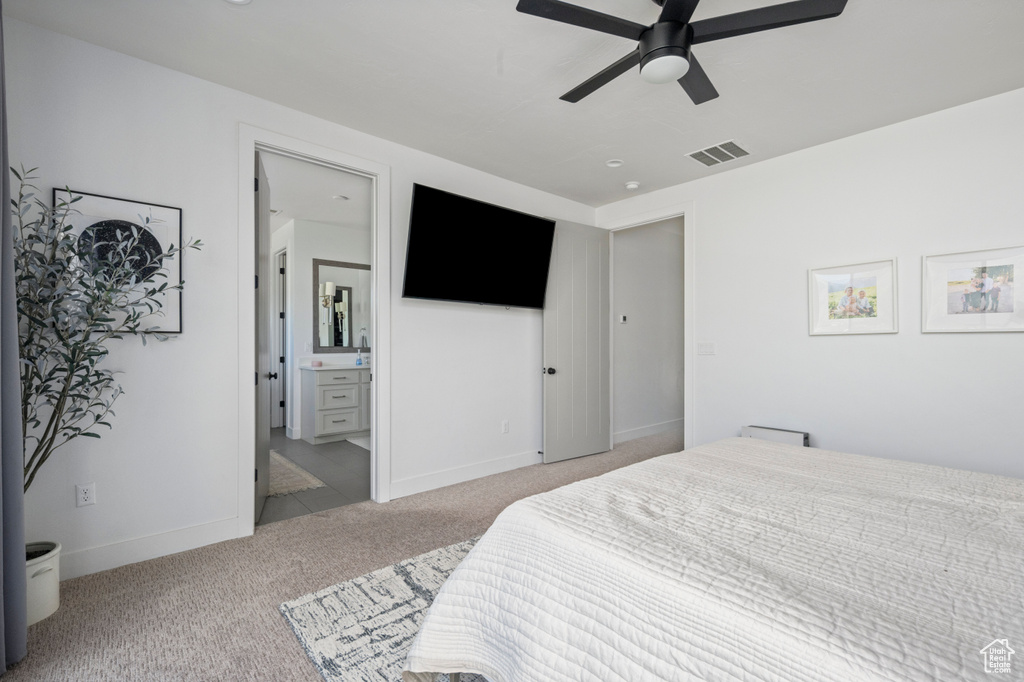 Carpeted bedroom featuring baseboards, ensuite bath, and ceiling fan