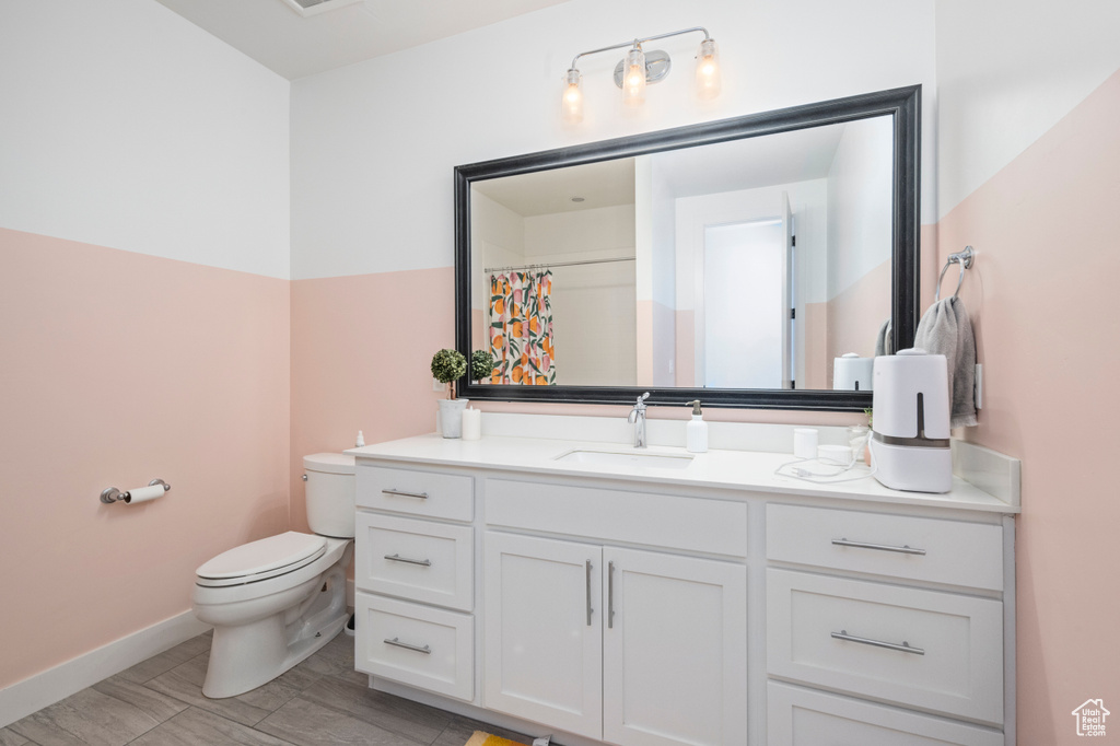 Bathroom with toilet, vanity, and baseboards