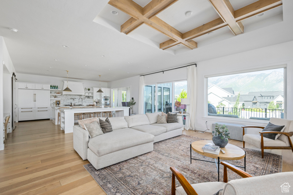 Living room with coffered ceiling, a barn door, light wood-type flooring, beam ceiling, and recessed lighting