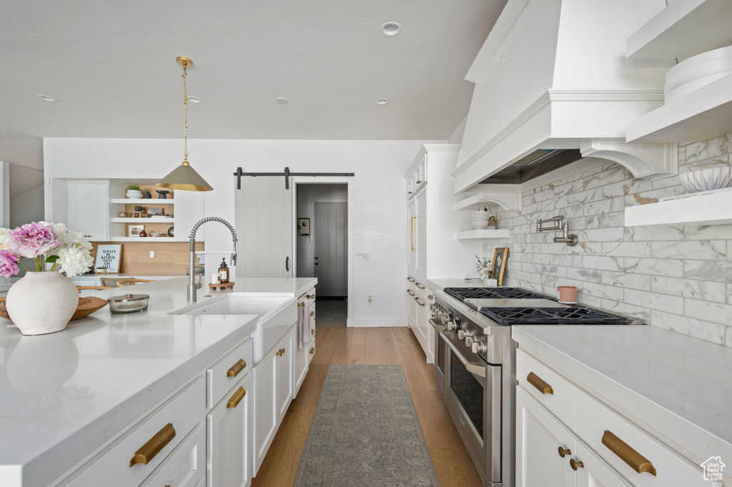 Kitchen featuring stainless steel range, open shelves, white cabinetry, decorative backsplash, and recessed lighting