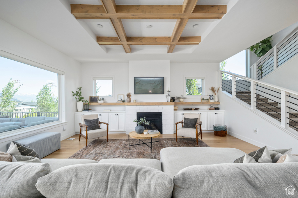 Living area with light wood-type flooring, healthy amount of natural light, baseboards, beamed ceiling, and coffered ceiling