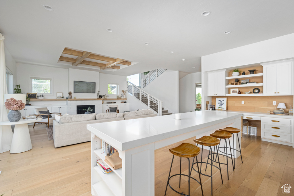 Kitchen with open shelves, coffered ceiling, a center island, recessed lighting, and light countertops